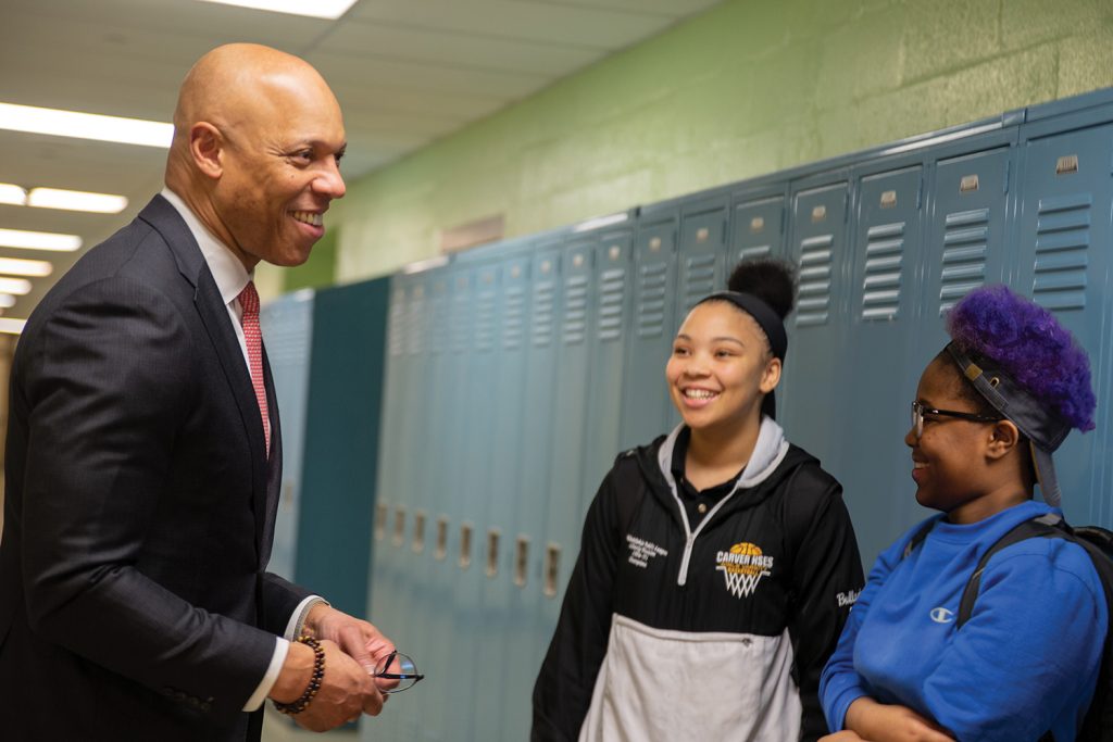 Dr. Hite smiling with two middle-school aged girls in front of lockers