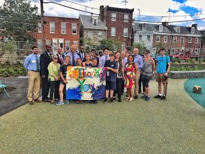 Students, Friends of Adaire Members and others pose with a Thank You Sign in the new school yard.