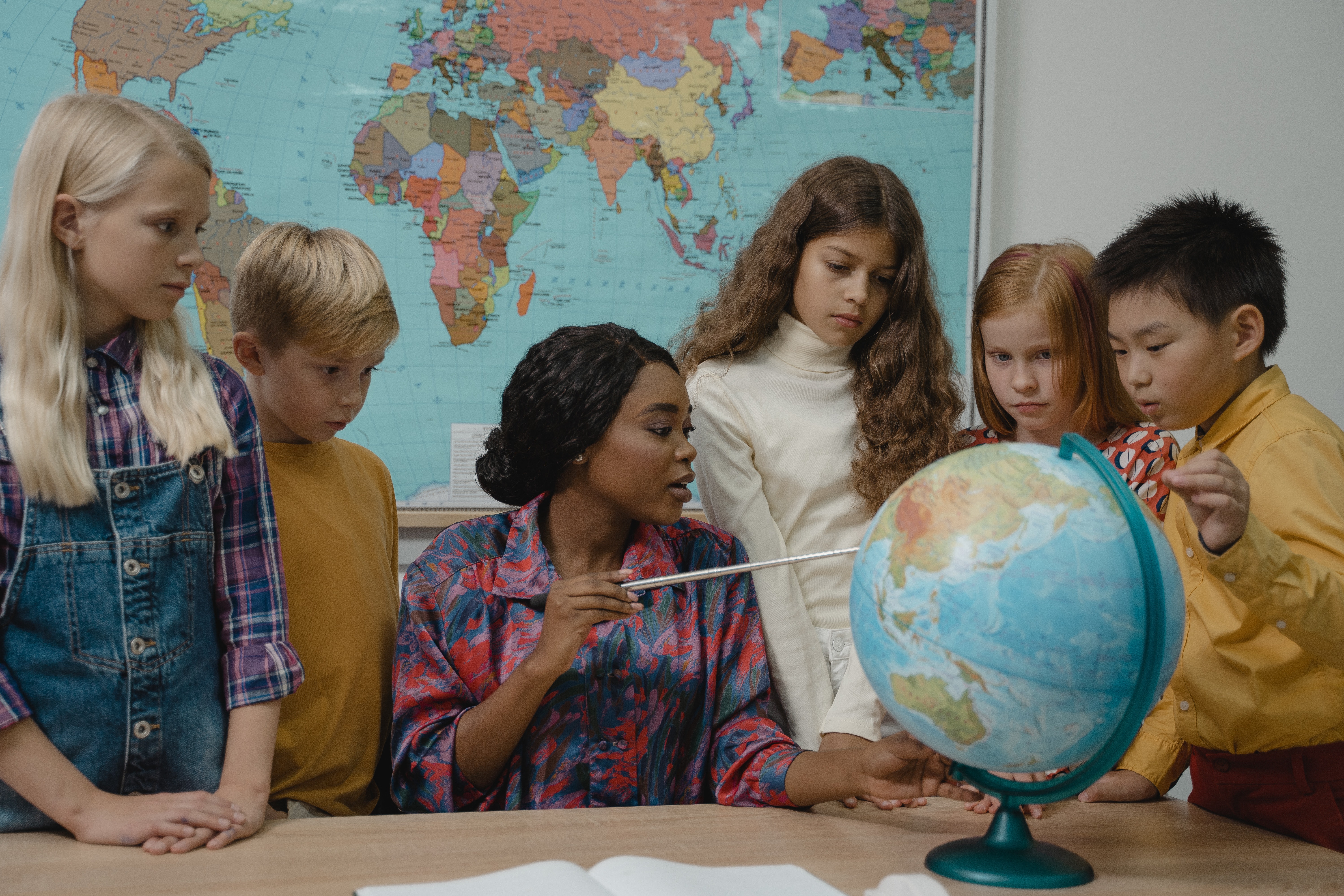 Teacher teaching students around a globe