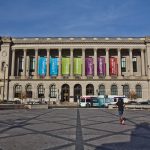 Facade of Free Library of Philadelphia on Vine Street, with runner in foreground. Library has large columns with colorful banners between them.
