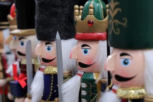 Several nutcrackers with hats and mustaches lined up.