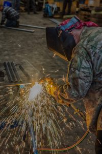 An iron-worker using a welding torch to create a frame for a project.