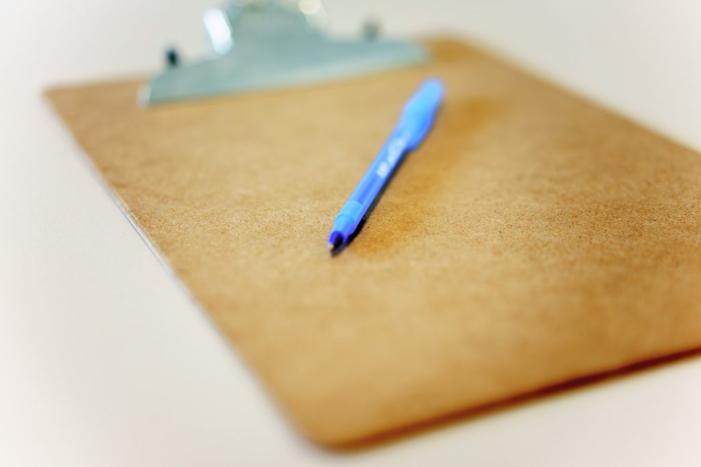 Office clipboard and blue pen