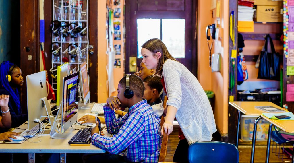 A teacher is helping her students with their computer assignments.