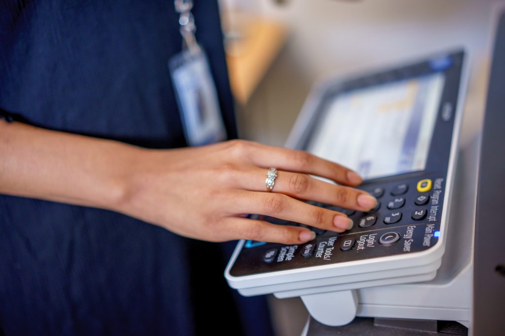 A woman's hand typing at a copier
