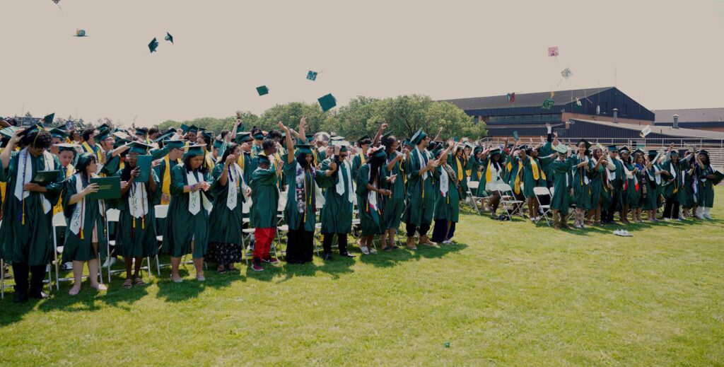 Graduates in a field throwing their caps in the air after the ceremony