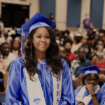 Student in blue graduation gown standing at graduation