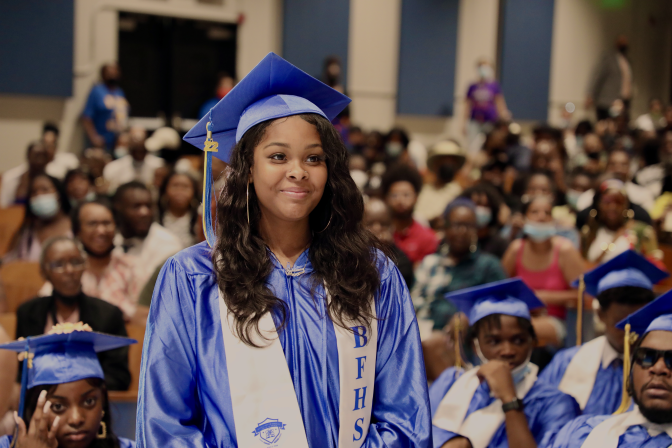 Student in blue graduation gown standing at graduation
