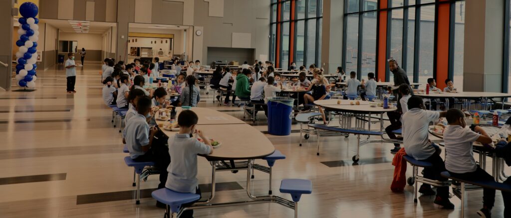 A wide shot of a well-lit cafeteria during student lunch time