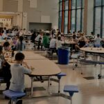 A wide shot of a well-lit cafeteria during student lunch time