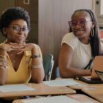 Two SDP high school students sitting at desks and smiling at the camera