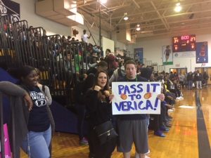 Teachers routing on their coleague during the games with a sign saying "Pass it to Verica"