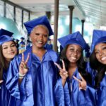 Four smiling graduation women in caps and gown