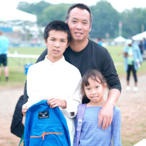 Father with two children outdoors, smiling together.