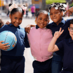 five young students in playground with colorful balls, smiling