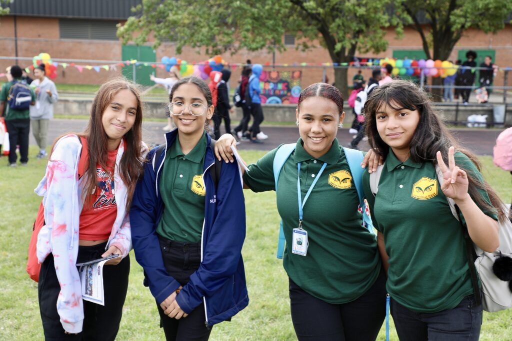 four middle school girls smiling in schoolyard on grass