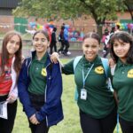 four middle school girls smiling in schoolyard on grass