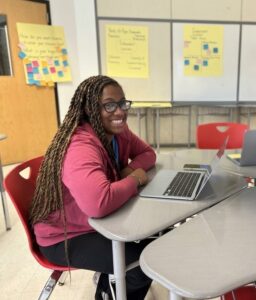 Ashley Still, smiling at a laptop and desk