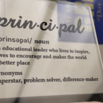 Plaque defining a principal as “an educational leader who lives to inspire, loves to encourage and makes the world a better place.” Synonyms listed: superstar, problem solver, difference-maker.